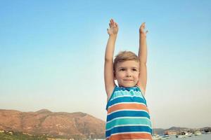 Small boy with raised arms on beach. photo