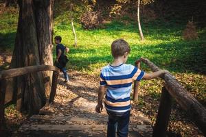 Rear view of kids crossing over wooden bridge in nature. photo