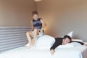 Boy in blurred motion jumping on the bed while playing with is father. photo