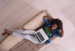 African American woman using laptop on sofa top view photo