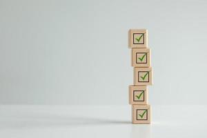 Checklist, Task list, Survey and assessment. Quality Control. Goals achievement and business success. Check mark icon on wooden blocks. photo