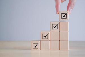 Checklist, Task list, Survey and assessment, Quality Control, Goals achievement and business success. Elections and Voting, Vote, to do list, Hand holding Check mark on ladder stack wooden blocks. photo