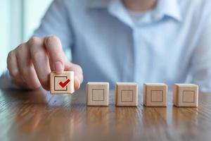 Elections and Voting, Vote, to do list, checklist, Task list, Survey and assessment concept. Hand holding check mark on wooden block and blank check box on wooden cubes. photo