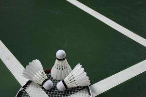 Cream white badminton shuttlecock and racket on red floor in indoor badminton court, copy space, soft and selective focus on shuttlecocks. photo