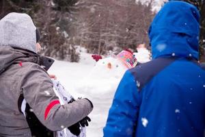 group of young people making a snowman photo