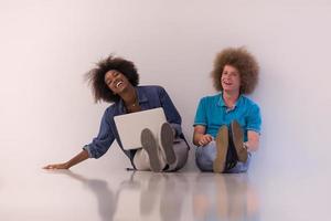 pareja multiétnica sentada en el suelo con una laptop y una tableta foto