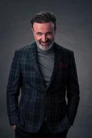 Portrait of a stylish elegant senior businessman with a beard and casual business clothes in photo studio isolated on dark background gesturing with hands