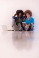 multiethnic couple sitting on the floor with a laptop and tablet photo