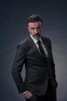 retrato de un elegante hombre de negocios de alto nivel con barba y ropa informal de negocios en un estudio fotográfico aislado en un fondo oscuro gesticulando con las manos foto