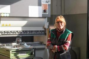 portrait of a woman standing in front of a CNC machine in goggles and working in a modern metal production and processing factory photo