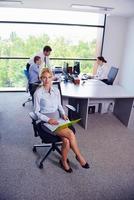 business woman with her staff in background at office photo