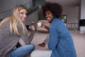 young multiethnic women sit on the floor and drinking coffee photo