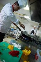 chef in hotel kitchen prepare food with fire photo