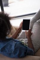 African american woman at home in chair with tablet and head phones photo