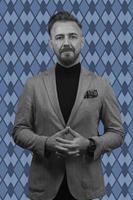 Black and white portrait of a stylish elegant senior businessman with a beard and casual business clothes against retro colorful pattern design background gesturing with hands photo