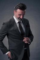 Portrait of a stylish elegant senior businessman with a beard and casual business clothes in photo studio isolated on dark background gesturing with hands