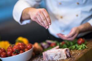 Chef putting salt on juicy slice of raw steak photo