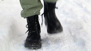 davanti Visualizza di un' congelato in piedi uomo nel nero stivali nel inverno. lasso di tempo di tremante neve a partire dal stivali nel inverno a il Ingresso per il Casa. tremante via neve a partire dal scarpe, pesante nevicata nel inverno. video