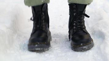 vista frontal de um homem em pé congelado em botas pretas no inverno. lapso de tempo de sacudir a neve das botas no inverno na entrada da casa. sacudindo a neve dos sapatos, forte nevasca no inverno. video