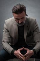 retrato de un elegante hombre de negocios de alto nivel con barba y ropa informal de negocios en un estudio fotográfico aislado en un fondo oscuro gesticulando con las manos foto