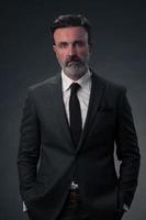 retrato de un elegante hombre de negocios de alto nivel con barba y ropa informal de negocios en un estudio fotográfico aislado en un fondo oscuro gesticulando con las manos foto