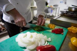 chef in hotel kitchen  slice  vegetables with knife photo