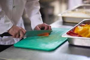 chef in hotel kitchen  slice  vegetables with knife photo