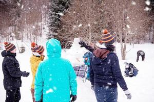 group of young people making a snowman photo