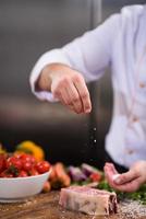 Chef putting salt on juicy slice of raw steak photo