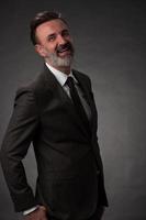 retrato de un elegante hombre de negocios de alto nivel con barba y ropa informal de negocios en un estudio fotográfico aislado en un fondo oscuro gesticulando con las manos foto