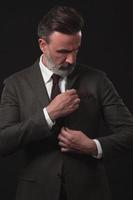 retrato de un elegante hombre de negocios de alto nivel con barba y ropa informal de negocios en un estudio fotográfico que ajusta el traje foto