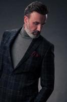 retrato de un elegante hombre de negocios de alto nivel con barba y ropa informal de negocios en un estudio fotográfico aislado en un fondo oscuro gesticulando con las manos foto