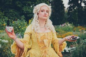 Portrait of blonde woman dressed in historical Baroque clothes with old fashion hairstyle, outdoors. photo