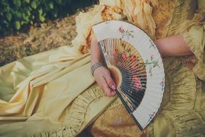 Luxurious medieval hand fan in the female hand, close-up photo