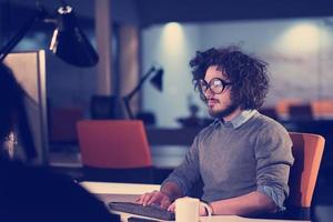 man working on computer in dark startup office photo