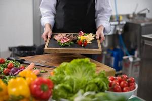 female Chef holding beef steak plate photo