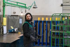 un retrato de una mujer uniformada que lleva una pieza de metal y la prepara para la parte final de la producción foto