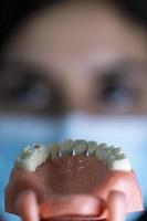 The woman dentist is holding dentures in his hands and instruments photo