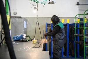 a woman working in the modern metal production and processing industry welding the product and prepares it for a cnc machine photo