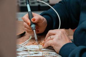 mujer trabajadora industrial soldando cables de equipos de fabricación en una fábrica foto