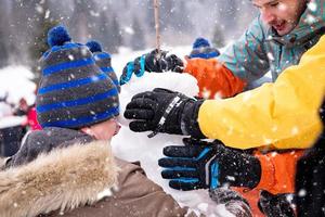 group of young people making a snowman photo