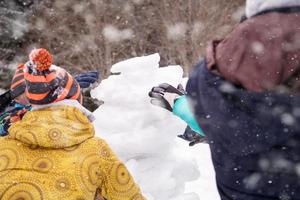 group of young people making a snowman photo
