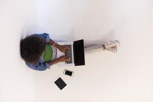 african american woman sitting on floor with laptop top view photo