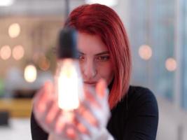 businesswoman holding hand around light bulb photo