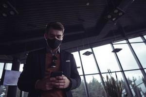 business man wearing coronavirus  medical face mask while using smartphone photo
