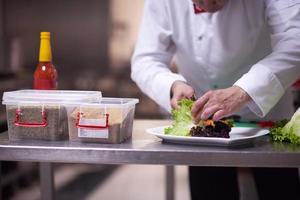 chef in hotel kitchen preparing and decorating food photo