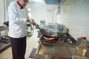 chef in hotel kitchen prepare food with fire photo