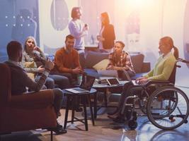 Handicapperd businesswoman in a wheelchair on meeting with her diverse business team brainstorming at office photo