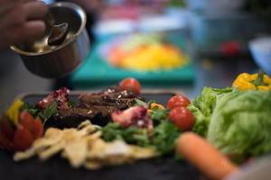 Chef hand finishing steak meat plate photo