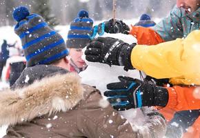 group of young people making a snowman photo